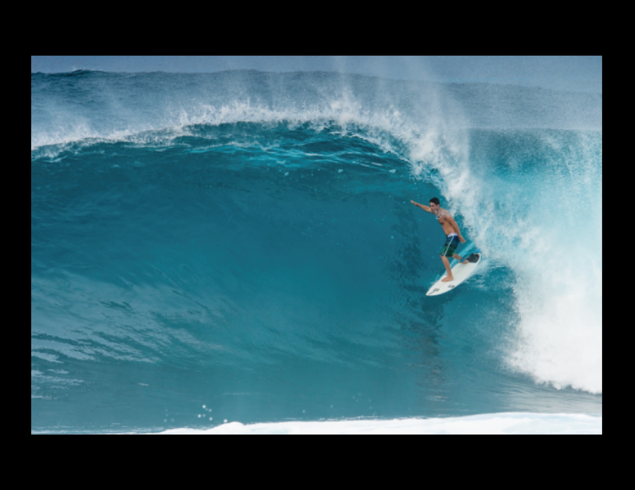 Surfer riding inside a blue barrel